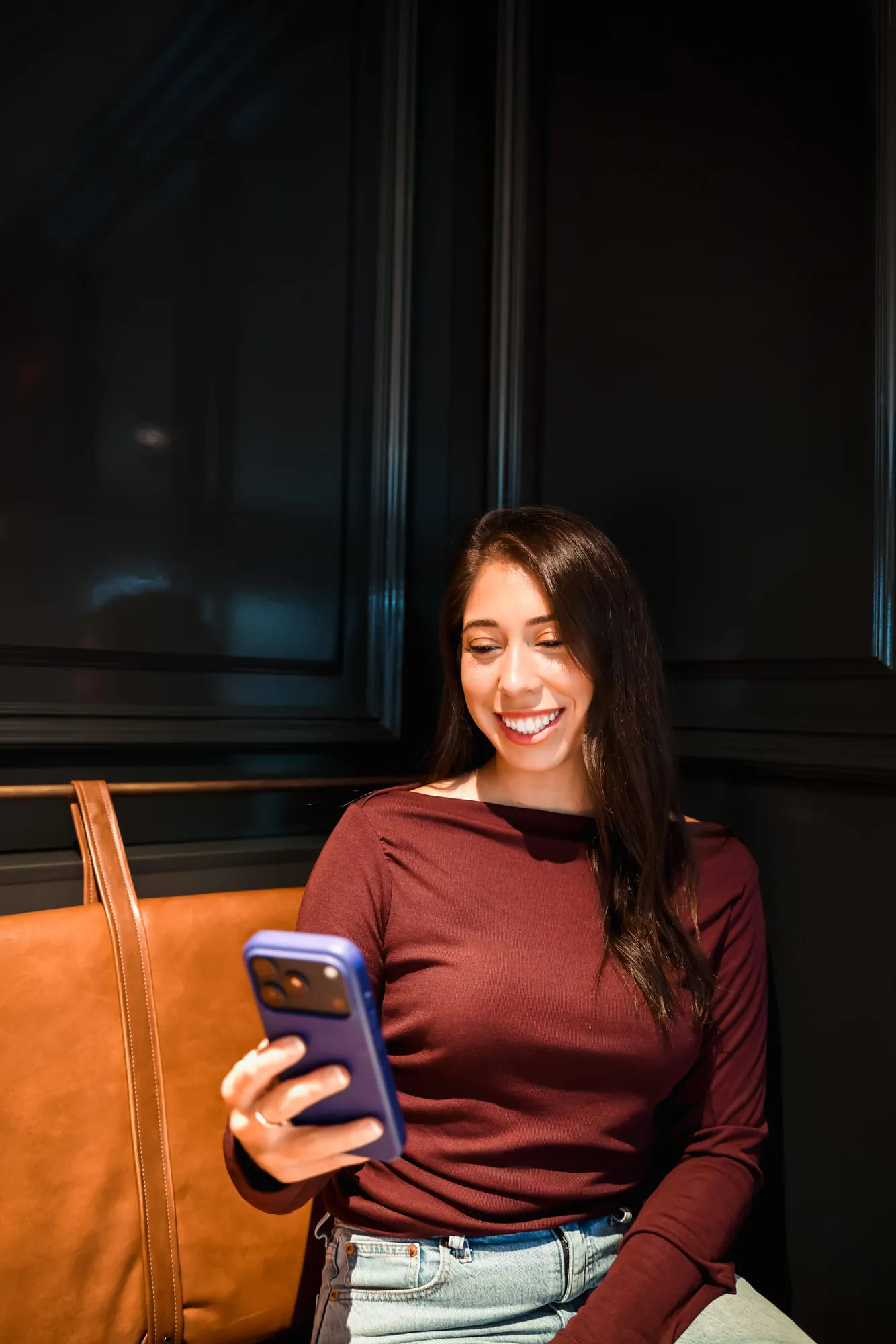 Lacey laughing at her phone in a leather booth